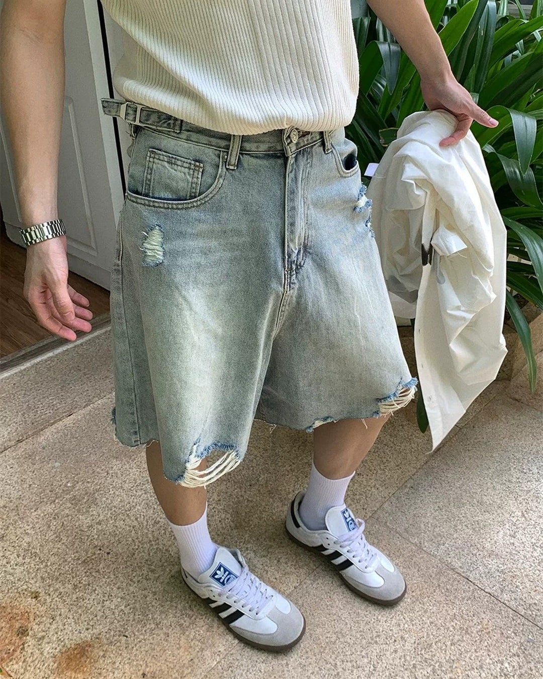Light blue distressed raw-hem denim shorts, close front showing distressed thigh