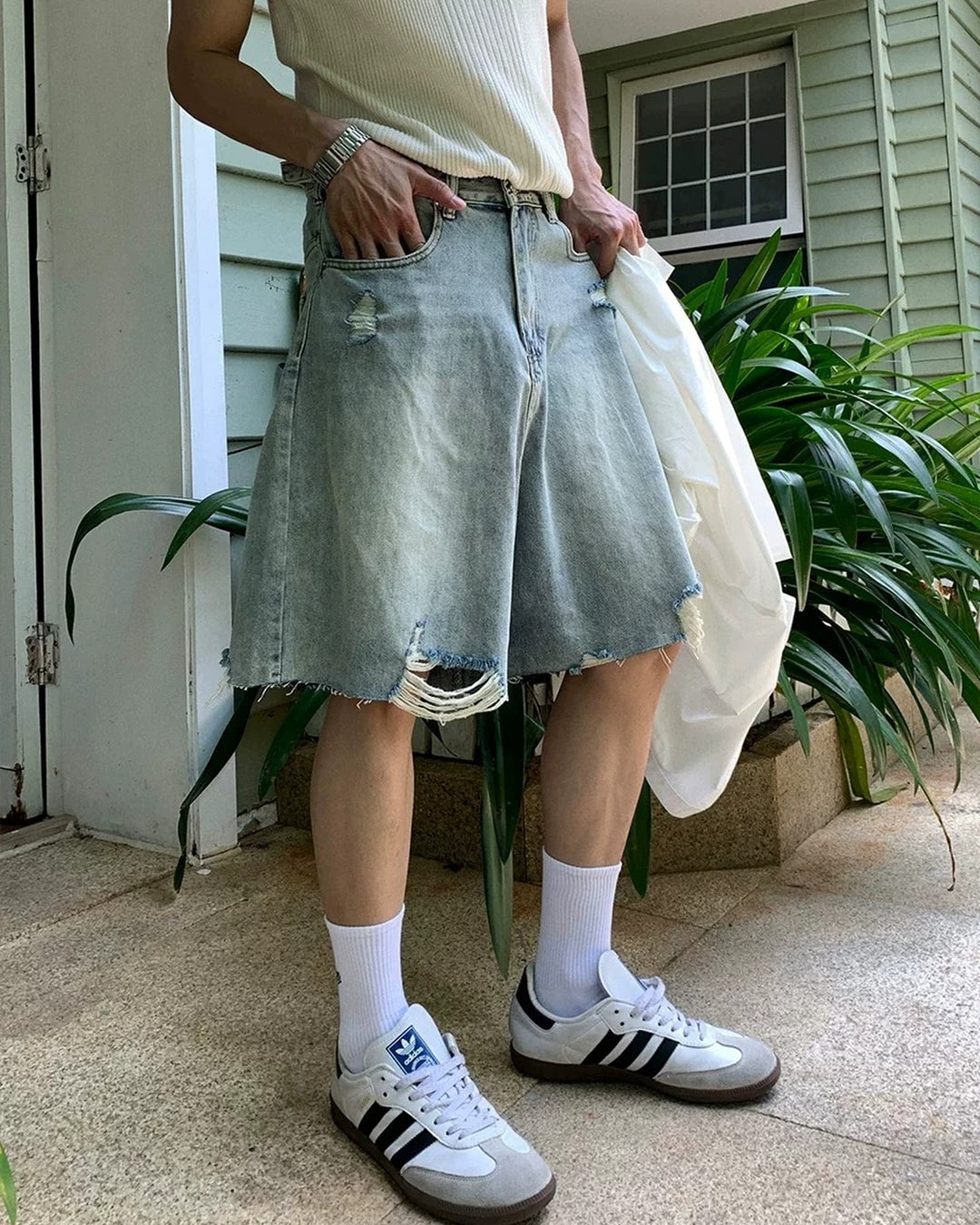 Light blue distressed raw-hem denim shorts, angled front with raw hems