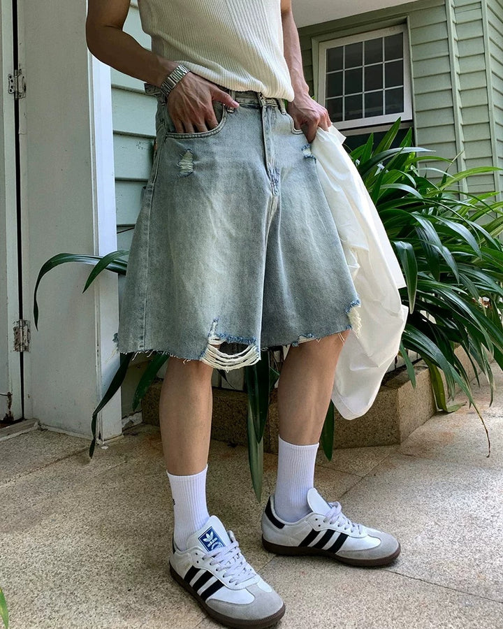 Light blue distressed raw-hem denim shorts, angled front with raw hems
