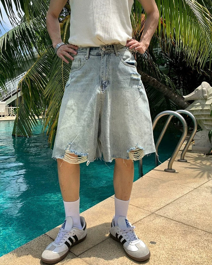 Light blue distressed raw-hem denim shorts, full front showing roomy legs