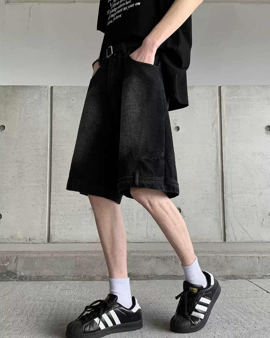 Vintage-wash wide-leg denim shorts, black, side styling with sneakers