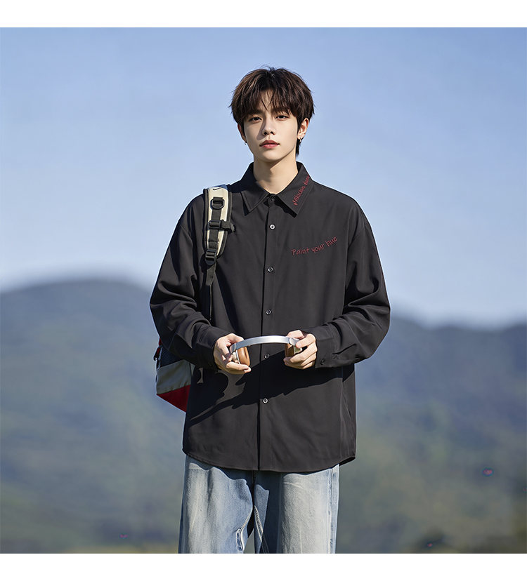 Script-embroidered shirt, angled view with a shoulder bag