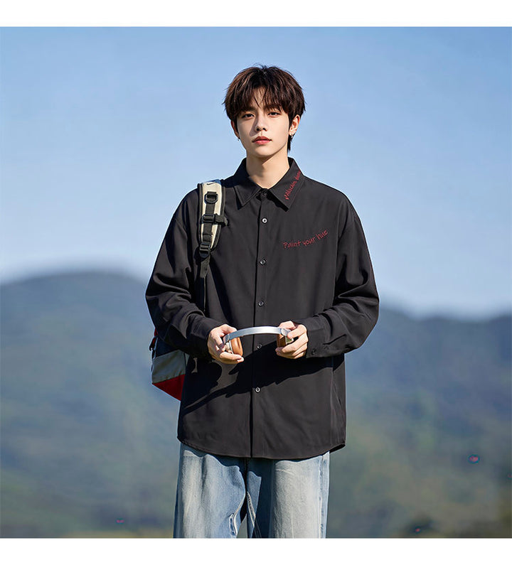 Script-embroidered shirt, angled view with a shoulder bag